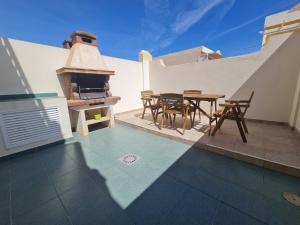 un patio con mesa, sillas y horno de pizza en We Fuerteventura, en Caleta de Fuste