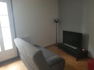 een woonkamer met een bank en een flatscreen-tv bij Maison de village proche de l'étang et de la mer in Marseillan