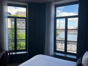 a bedroom with two windows with a view of the water at U Eat & Sleep Antwerp in Antwerp