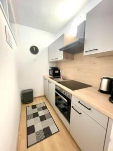 cocina con armarios blancos y suelo a cuadros en blanco y negro en **Modernes Apartment in zentraler Lage**, en Graz