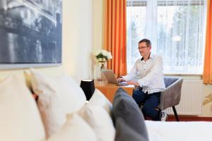 um homem sentado numa secretária com um portátil em SCHÖNBRUNN Hotel em Schönbrunn