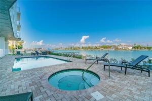 a swimming pool with chairs next to a body of water at Oceana 301 East in St Pete Beach