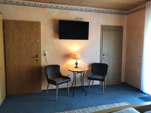 Zimmer mit einem Tisch, 2 Stühlen und einem TV in der Unterkunft Moselpension Gwosch in Bruttig-Fankel