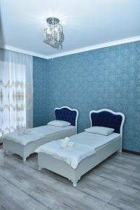 two beds in a room with a blue wall at Gabala White House in Gabala