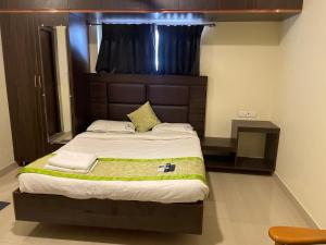 Schlafzimmer mit einem großen Bett mit einem Kopfteil aus Holz in der Unterkunft Tranquil Park in Puducherry