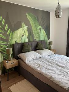 a bedroom with a bed with a mural of leaves at Zamárdi Margittai Apartmanok in Zamárdi