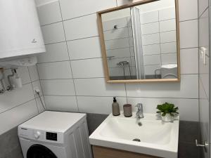 a white bathroom with a sink and a mirror at Zamárdi Margittai Apartmanok in Zamárdi