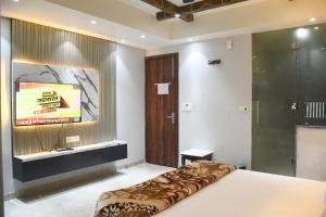 een slaapkamer met een bed en een televisie aan de muur bij Hotel Imperial Crown in Rewāri