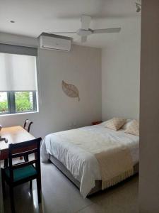 1 dormitorio con cama, escritorio y ventana en Beachfront Apartment, en Tamarin