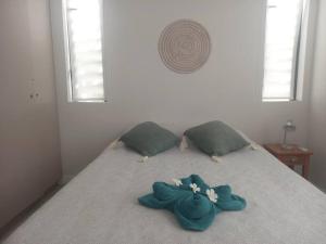Bett mit blauem Bogen und zwei Kissen in der Unterkunft Beachfront Apartment in Tamarin