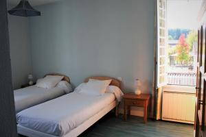 2 Betten in einem kleinen Zimmer mit Fenster in der Unterkunft Hôtel Chez Léonie - Chez Mamie Canne in Eugénie-les-Bains