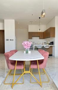 a dining room with a white table and pink chairs at Spacious new 2 bedroom Apt-in amazing location B6 in Riyadh