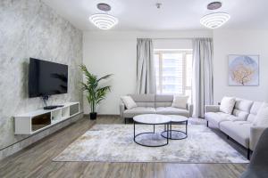 a living room with white furniture and a flat screen tv at Veluxa - Large and Stylish 1 Bed in JLT! in Dubai