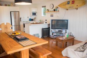 a living room with a table and a television at Nigel's Crib - Coopers Beach Holiday Home in Coopers Beach