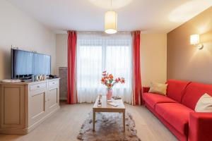uma sala de estar com um sofá vermelho e uma televisão em Zenao Appart'hôtels Strasbourg em Estrasburgo