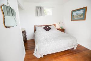 a bedroom with a white bed with a wooden floor at Nigel's Crib - Coopers Beach Holiday Home in Coopers Beach
