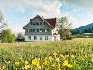 a house in the middle of a field with flowers at Alpenloge Boutique Hotel in Scheidegg