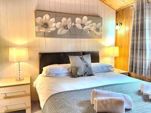 um quarto com uma cama e um quadro na parede em Snowdrop 13-Hot Tub-Woodlandlodges-Carmarthenshire em Carmarthen