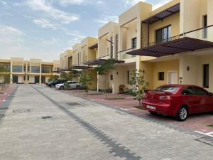 a red car parked in front of a row of buildings at Spacious 3BR Townhouse Villa in Dubai