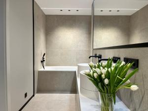 a bathroom with a vase of flowers on a counter at Apartamenty Małgorzaty Sobczak in Jelenia Góra +33 photos