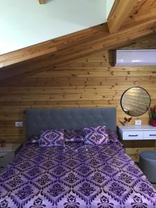 a bedroom with a purple bed with a wooden wall at Wooden Guest House in Bamatat