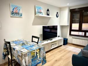 sala de estar con mesa y TV de pantalla plana en Apartamento Barrio de la Arena, en Gijón
