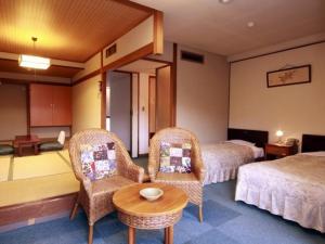 una camera d'albergo con due letti e un tavolo con sedie di Breezbay Shuzenji Hotel a Izu