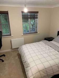 a bedroom with a large bed and two windows at Thames River Side Townhouse in Thamesmead