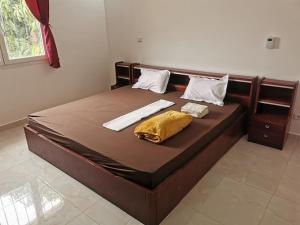 een groot bed met een houten frame en een geel kussen bij CasaCanda Tout confort 300 m de la mer in Somone
