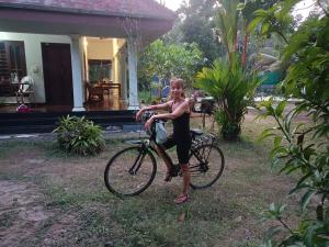 a woman riding a bike in front of a house at Angels' homestay Marari in Mararikulam