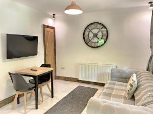 uma sala de estar com um sofá e um relógio na parede em BlueStone-Hot Tub-Woodlandlodges-Pembrokeshire-Tenby em Carmarthen