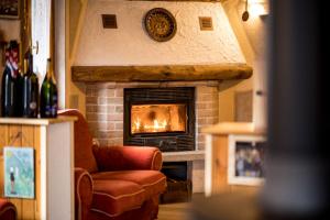 a living room with a fireplace with a clock on the wall at Chalet Relax Tra Le Vigne in Forni di Sotto