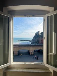 a window with a view of a beach and the ocean at Elegant apartment with sea view in Monterosso al Mare