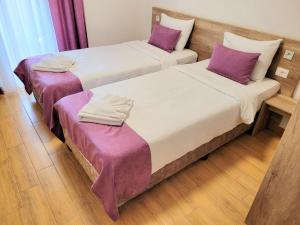 two beds in a room with purple sheets and pillows at Dona, Altina in Belgrade