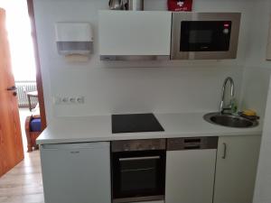 een witte keuken met een wastafel en een magnetron bij Lucky Home Sissi Appartment in Füssen