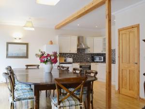 cocina y comedor con mesa de madera y sillas en Stable Cottage - Beaufort Estate, en Belladrum