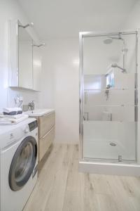a white bathroom with a washing machine and a shower at Dom nad Bychowianką in Białogóra