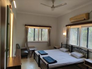 a bedroom with a bed and a desk and two windows at Vatika Homestay in Varanasi
