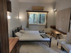 a room with two beds and a couch and a window at Vatika Homestay in Varanasi