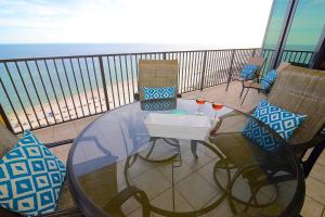 a glass table and chairs on a balcony with the beach at Oasis at Orange Beach 1103 in Orange Beach