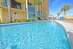 a swimming pool in front of a building with palm trees at Oasis at Orange Beach 1103 in Orange Beach