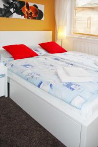 duże białe łóżko z czerwonymi poduszkami w obiekcie Apartmány Rokytka u sjezdovky w Rokitnicach nad Izerą
