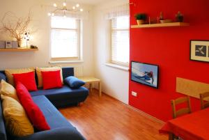 a living room with a blue couch and a red wall at Apartmány Rokytka u sjezdovky in Rokytnice nad Jizerou