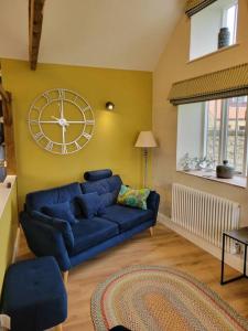 達靈頓的住宿－The Woodshop，客厅配有蓝色的沙发和墙上的时钟