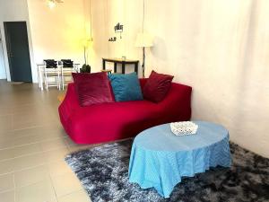a red couch in a living room with a table at Home33#2pax#wifi&netflix#NearAeonAlma#5kmIconCity#5kmtoSimpangAmpat in Bukit Mertajam