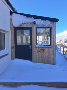a wooden building with a door in the snow at NC500 - Modern croft house at Handa in Scourie