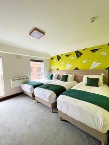 2 camas en una habitación con paredes amarillas y verdes en The Norseman Temple Bar, en Dublín