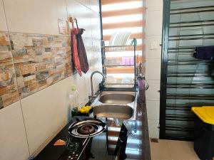 uma cozinha com um lavatório e uma prateleira com um estendal em Naira Homestay Kota Bharu ,Wakaf Che Yeh 4 Bilik 3 Aircond em Kota Bharu