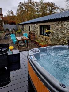a large hot tub on the deck of a house at Fyne Byre Cottage - Barn Conversion with Hot Tub in Cairndow