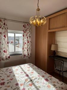 a bedroom with a bed and a chandelier and a window at Casa Pedro in Salema - Oceanview & beach in Salema